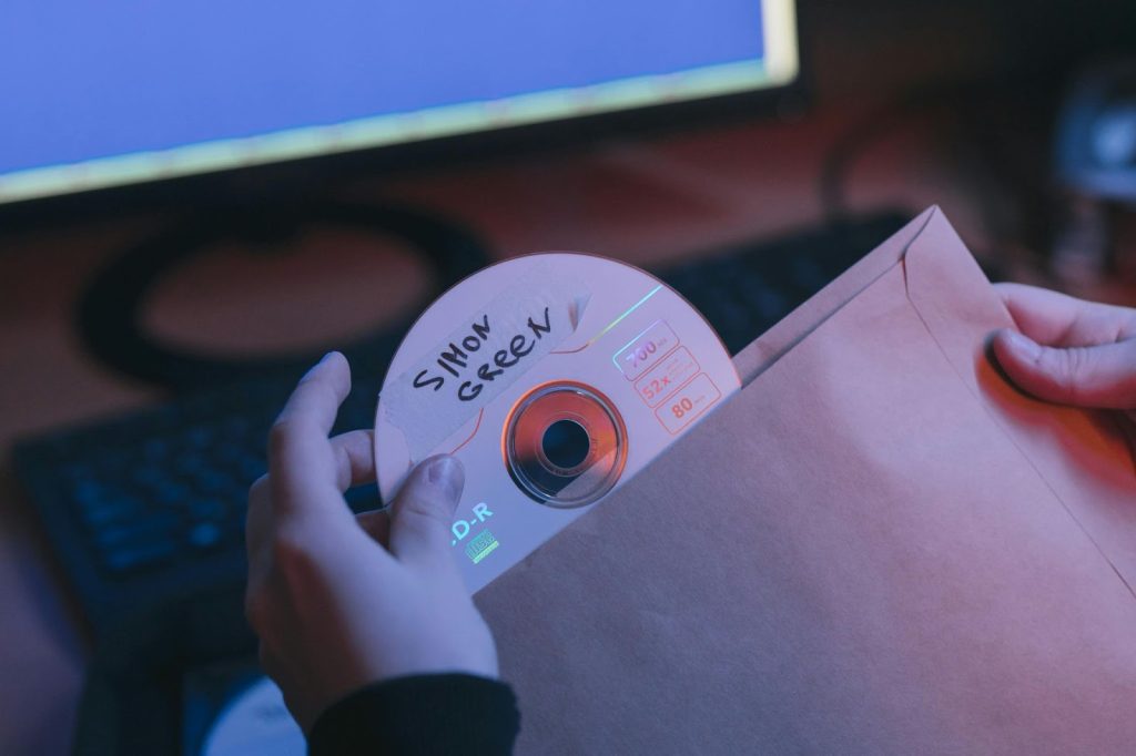 Imagem de uma pessoa segurando um CD com uma impressão usando uma caneta marcadora de CD